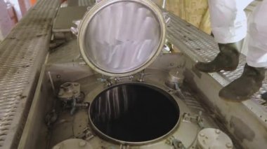 Kimyasal korumalı bir işçi kamyon tankının kapağını kapatıyor. Temizlik istasyonunda koruyucu takım elbiseli bir işçi. İşçi zararlı kimyasallarla çalışır.