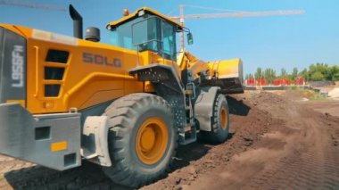 İnşaat alanında sarı traktör. İnşaat alanında çalışma süreci. Profesyonel inşaat ekipmanları.