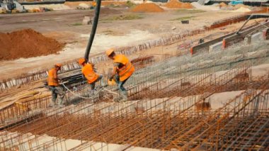 İnşaat alanında çalışma süreci. İşçiler güçlendirilmiş beton yapı yapıyorlar. Güçlendirilmiş beton. Metal bir yapıya beton dökülüyor..