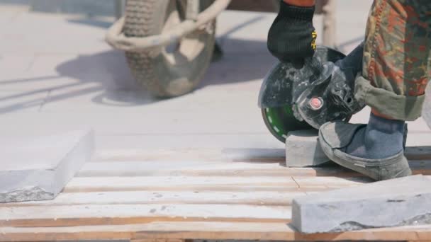 Robotnik kroi granitową płytę szlifierką. Proces pracy na placu budowy. Praca jako szlifierka na budowie — Wideo stockowe