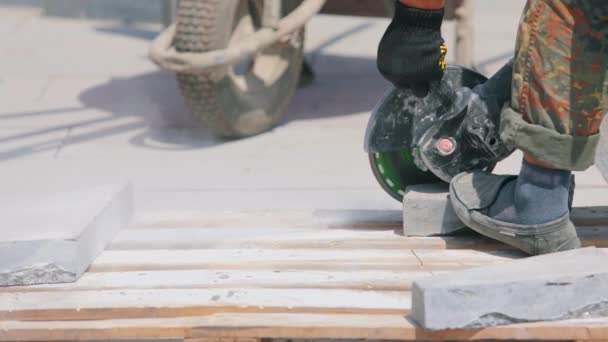 Un ouvrier coupe une dalle de granit avec une meuleuse. Processus de travail sur un chantier de construction. Travailler comme meuleuse sur un chantier — Video