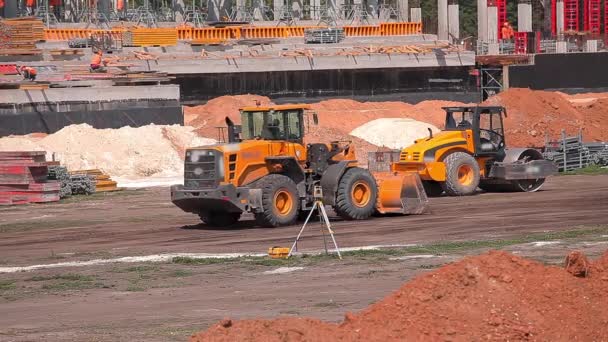 Żółty traktor na placu budowy. Proces pracy na placu budowy. Profesjonalny sprzęt budowlany. — Wideo stockowe