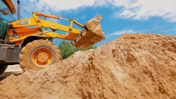 Un tractor cava un agujero en un sitio de construcción. Proceso de trabajo en una obra. Cubo del tractor de cerca — Vídeo de stock