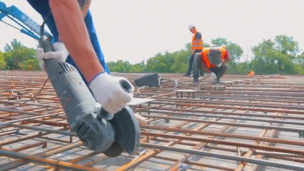 Un hombre trabaja con una sierra circular. Trabajador de la construcción corta barras de refuerzo con sierra circular — Vídeos de Stock