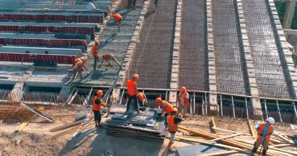 Bau eines modernen Fußballstadions. Bauarbeiter stellen Schalungen auf der Baustelle für ein neues Stadion her. Luftaufnahme der Stahlbetonkonstruktion — Stockvideo