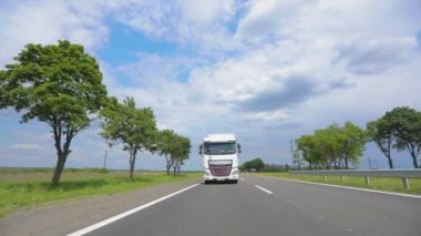 Otoyol boyunca giden beyaz bir kamyon. Tankerli bir kamyon güneşli havada otoyola çıkıyor. Bir kamyon konvoyu otoban boyunca gidiyor.