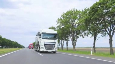 Otoyol boyunca giden beyaz bir kamyon. Güneşli bir havada otoyolda sürüş.