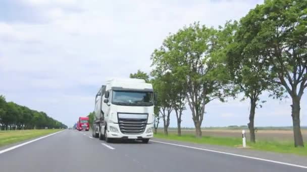 Белый грузовик едет по шоссе. Проезд по шоссе в солнечную погоду. — стоковое видео