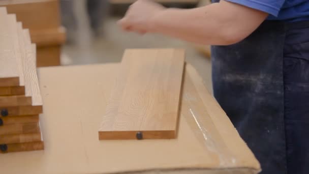 Шлифовка деревянной мебели. Рабочий шлифует деревянную деталь на мебельной фабрике. Процесс производства мебели — стоковое видео