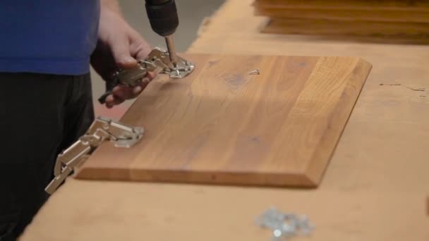 Montage van meubels in een fabriek. Een arbeider monteert houten meubels in een fabriek — Stockvideo