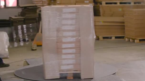 Erityinen kone käärii laatikot polyeteenikalvoon. Pakkauslaatikot, joissa on tuotteita muovikalvolla tehtaalla. — kuvapankkivideo