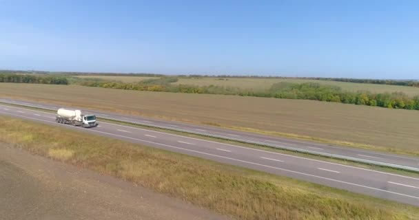 Lastbilen kör längs fälten i soligt väder. Lastbil kör på en vacker väg. Lastbilen kör längs fälten ovanifrån. — Stockvideo