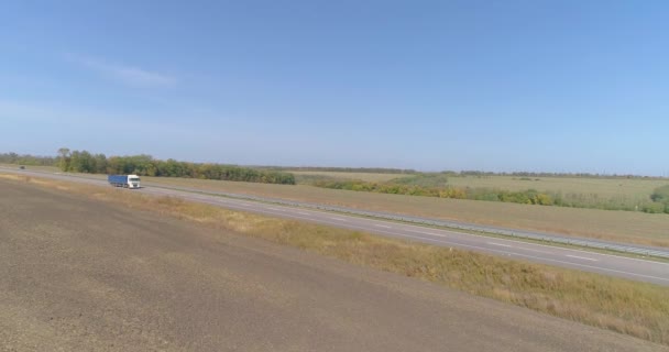 Ciężarówka jedzie po drodze, pola w tle. Ciężarówka jedzie wzdłuż drogi w środku pól rolniczych widok z góry. — Wideo stockowe