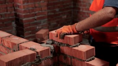 İnşaatçı tuğlaları diziyor. Bir tuğla duvar inşa etme süreci