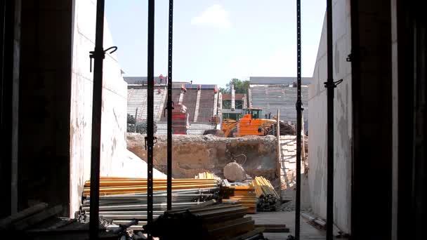 Uma grande escavadora amarela está dirigindo em um canteiro de obras. Construção moderna — Vídeo de Stock