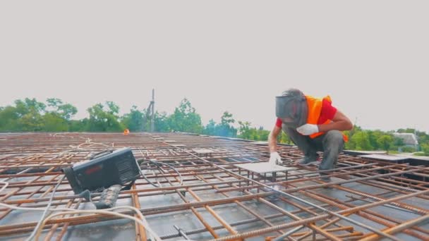 Soldador en una obra de construcción. Proceso de trabajo en una obra. Primer plano del soldador. Estructuras metálicas — Vídeo de stock