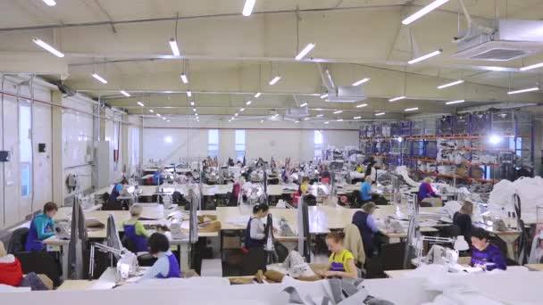 Las vueltas de tiempo en el taller de costura. Las mujeres trabajan en un taller de costura, filmando en vueltas de tiempo. Interior de la fábrica de ropa. — Vídeos de Stock