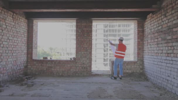 Ingenieros con un plano dentro de una casa nueva. Constructores dentro de un nuevo edificio. — Vídeos de Stock