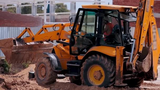 Trator amarelo em um local de construção. Equipamento de construção profissional. Processo de trabalho num estaleiro — Vídeo de Stock