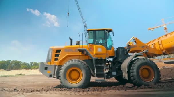 Trator moderno em um canteiro de obras. Grande tractor amarelo. Equipamento de construção profissional. Processo de trabalho num estaleiro — Vídeo de Stock