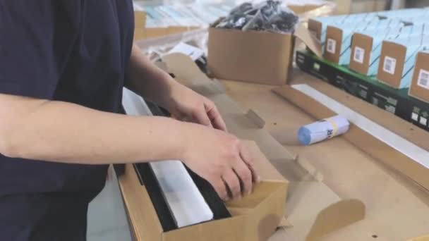 Verpakking van eindproducten in een doos. Werknemers verpakken afgewerkte producten in een doos — Stockvideo