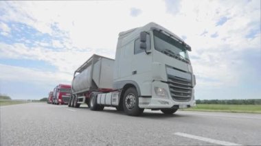 Tankerli bir kamyon güneşli havada otoyola çıkıyor. Otoyol boyunca giden beyaz bir kamyon. Bir kamyon konvoyu otoban boyunca gidiyor.