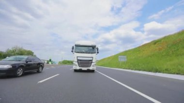 Otoyol boyunca giden beyaz bir kamyon. Güneşli bir havada otoyolda sürüş.