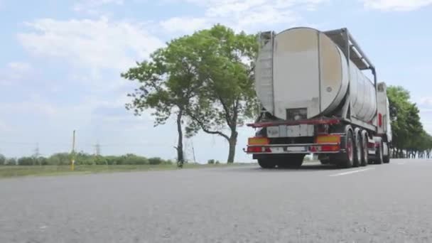 Ciężarówka z cysterną jedzie autostradą w słoneczną pogodę. Biała ciężarówka jadąca autostradą. Konwój ciężarówek jedzie wzdłuż autostrady. — Wideo stockowe