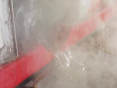 Borudan su akıyor, sıcak su buharlaşıyor. Endüstriyel suyun boşaltılması. Tankın kimyasal temizliğinden sonra atık su.