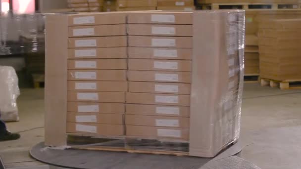 Cajas de embalaje con productos en película de plástico en la fábrica. Una máquina especial envuelve cajas en película de polietileno — Vídeo de stock