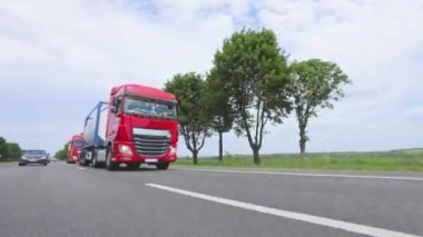 Kırmızı kamyon otoyol boyunca gidiyor. Bir grup kamyon otoyol boyunca gidiyor. Modern kamyonlar tanklarda sıvı kargo taşıyorlar