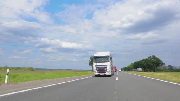 Weiße Lastwagen fahren die Autobahn entlang. Ein Lastwagen mit Tankwagen fährt bei sonnigem Wetter über die Autobahn. Ein Lastwagenkonvoi fährt über die Autobahn — Stockvideo