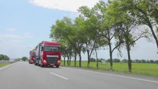 Czerwona ciężarówka jedzie autostradą. Grupa ciężarówek jedzie wzdłuż autostrady. Nowoczesne samochody ciężarowe przewożą ładunki płynne w cysternach — Wideo stockowe
