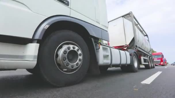 Los camiones están conduciendo por la carretera. Un camión con un camión cisterna conduce a lo largo del primer plano de la carretera. Transporte de mercancías peligrosas — Vídeo de stock