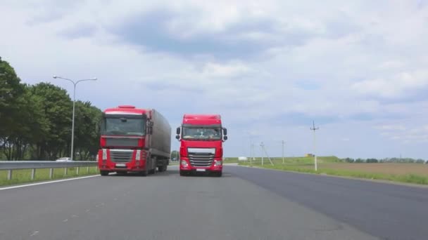 A piros teherautó az autópálya mentén halad. Egy csapat teherautó halad végig az autópályán. A modern teherautók folyékony rakományt szállítanak tartályban — Stock videók