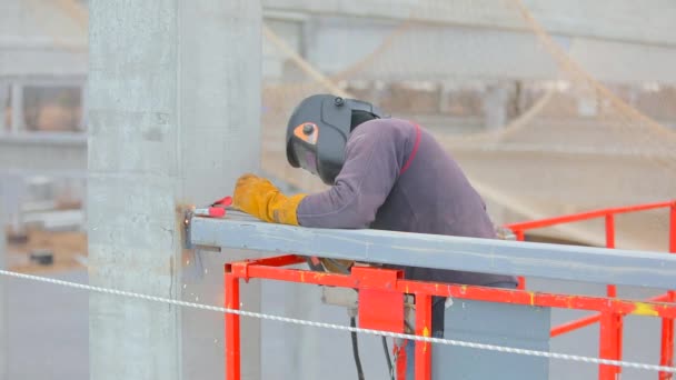 Muž ve výtahu svařuje kovovou konstrukci. Pracovní postup na staveništi. Svařování kovových konstrukcí — Stock video