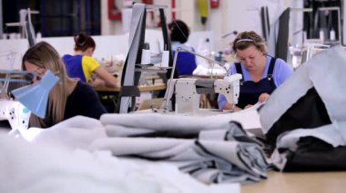 Bir giyim fabrikasında çalışma süreci. Birçok terzi bir giyim fabrikasında çalışır. Büyük dikiş atölyesi. Terziler fabrikada ürün yapar. Kumaş fabrikası