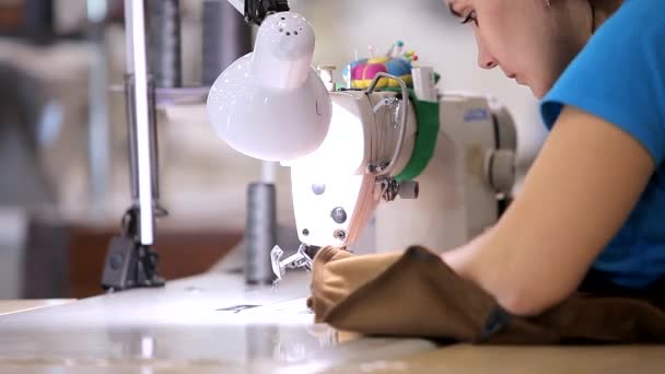 Uma mulher trabalha numa fábrica de vestuário. Uma mulher trabalha numa máquina de costura. Fazendo têxteis em uma fábrica — Vídeo de Stock