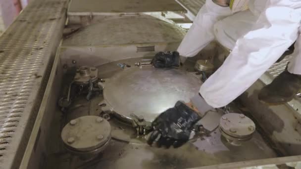 Kimyasal korumalı bir işçi kamyon tankının kapağını kapatıyor. Temizlik istasyonunda koruyucu takım elbiseli bir işçi. İşçi zararlı kimyasallarla çalışır. — Stok video