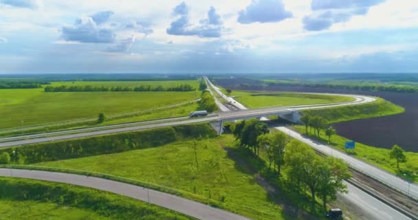 Дорожный узел на современном шоссе с видом с воздуха. Современная дорога, вокруг зеленого мегаполиса — стоковое видео
