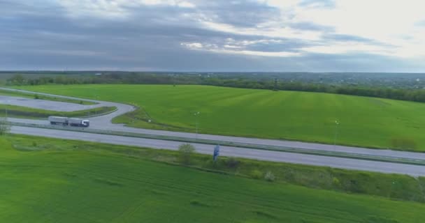 Náklaďák na dálnici z dronu. Nákladní automobily jezdí na moderní dálnici kolem zelené trávy horní pohled — Stock video