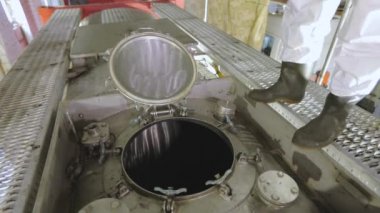 Kimyasal korumalı bir işçi kamyon tankının kapağını kapatıyor. Temizlik istasyonunda koruyucu takım elbiseli bir işçi. İşçi zararlı kimyasallarla çalışır.