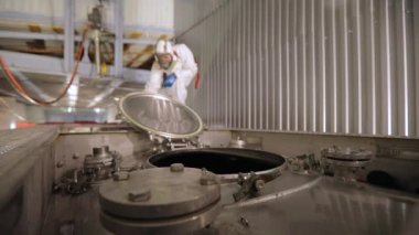 Bir işçi içeriden buharlı bir tank kamyonunun kimyasal temizliğini yapıyor. Tankerin otomatik buhar temizliği. Kimyasal koruma işçisi