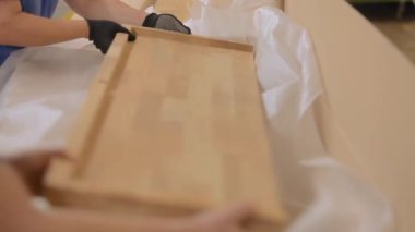 Bitmiş malların bir kutuda paketlenmesi. İşçiler bitmiş ürünleri bir kutuya doldururlar