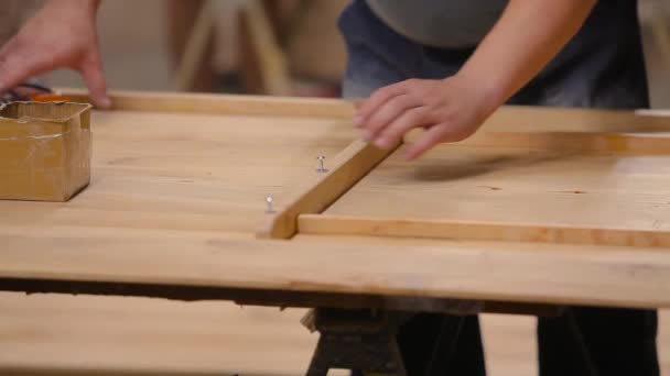 Montage van meubels in een fabriek. Een arbeider monteert houten meubels in een fabriek — Stockvideo