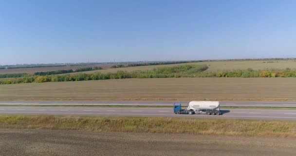 Carro conduciendo a lo largo de la carretera de tiro con drones. El camión está conduciendo a lo largo de la carretera, la naturaleza está alrededor. El camión conduce a lo largo de un largo camino recto. — Vídeo de stock