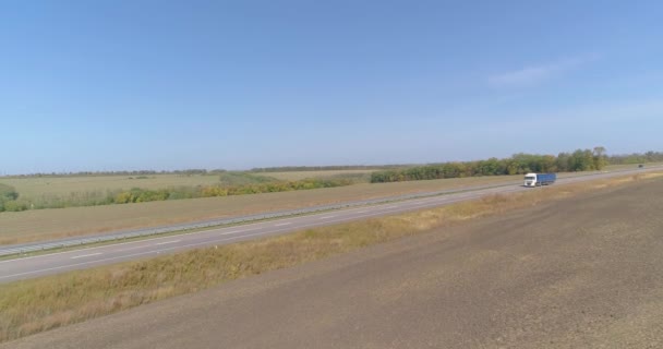 道路のドローン撮影に沿ってワゴンの運転。トラックは道路に沿って運転され、自然が周りにあります。トラックは長い直線道路に沿って運転します. — ストック動画