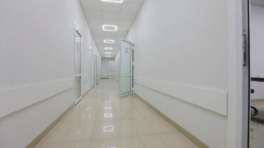 Kliniğin boş, parlak koridoru. Modern bir kliniğin içinde. Modern bir hastanenin koridorları. Kamera hastanenin boş koridoru boyunca dönüyor..