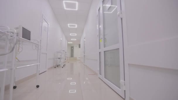 Interior of a modern clinic. The empty, bright corridor of the clinic. Corridors of a modern hospital. The camera pans along the empty hallway of the hospital. — Vídeo de Stock