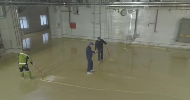 Trabajadores en la obra. Los trabajadores hacen el piso en el taller de la planta. Construcción de un nuevo taller en la planta — Vídeos de Stock